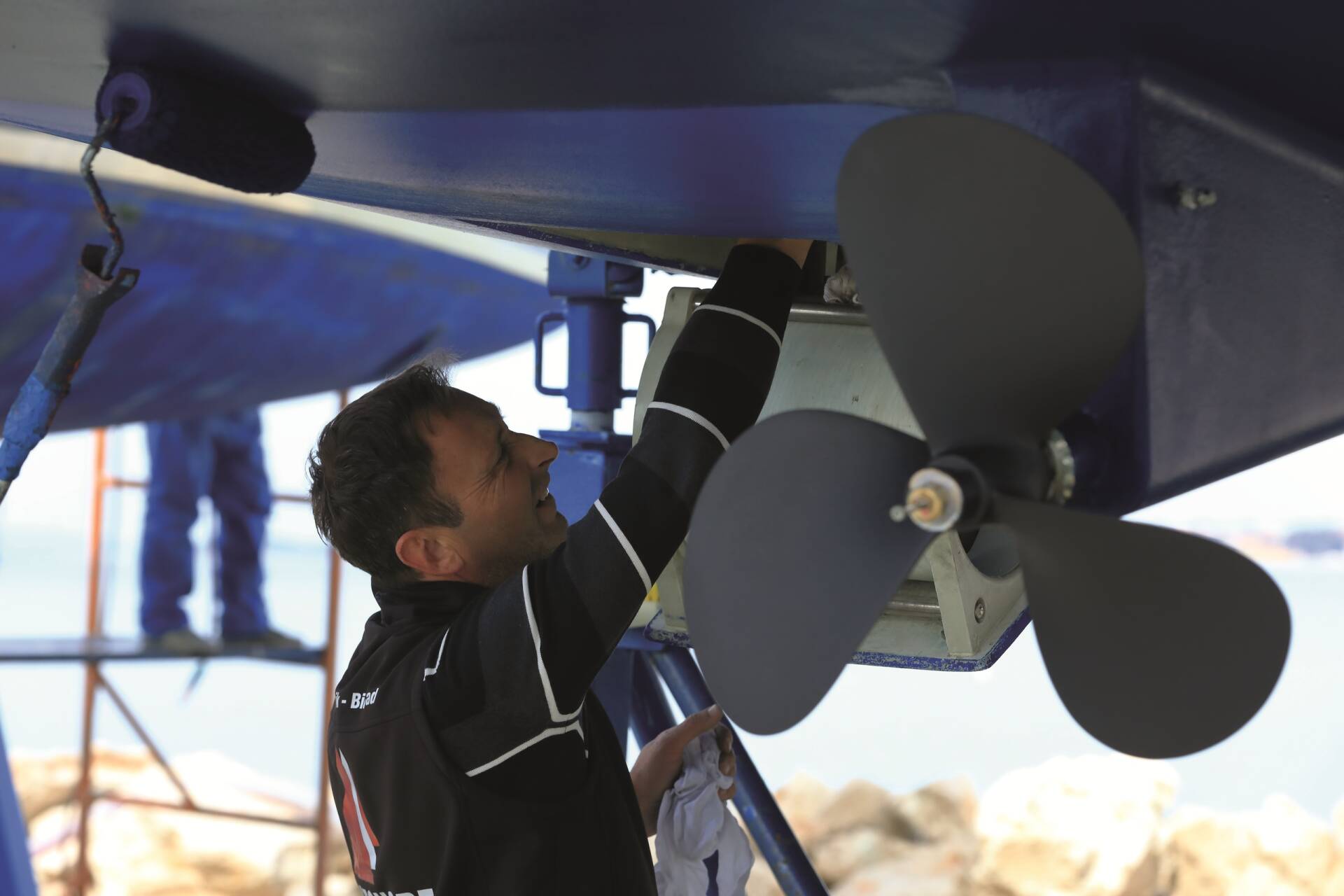 Mann überprüft den Bereich unter einem Boot neben der Schiffsschraube.